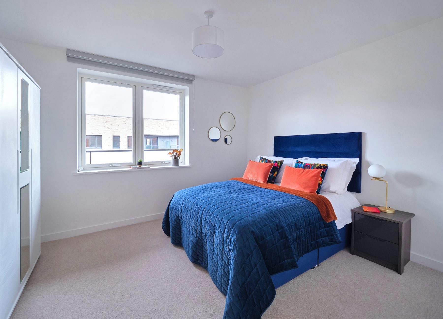 Beautiful blue and orange divan bed in a white spacious bedroom apartment